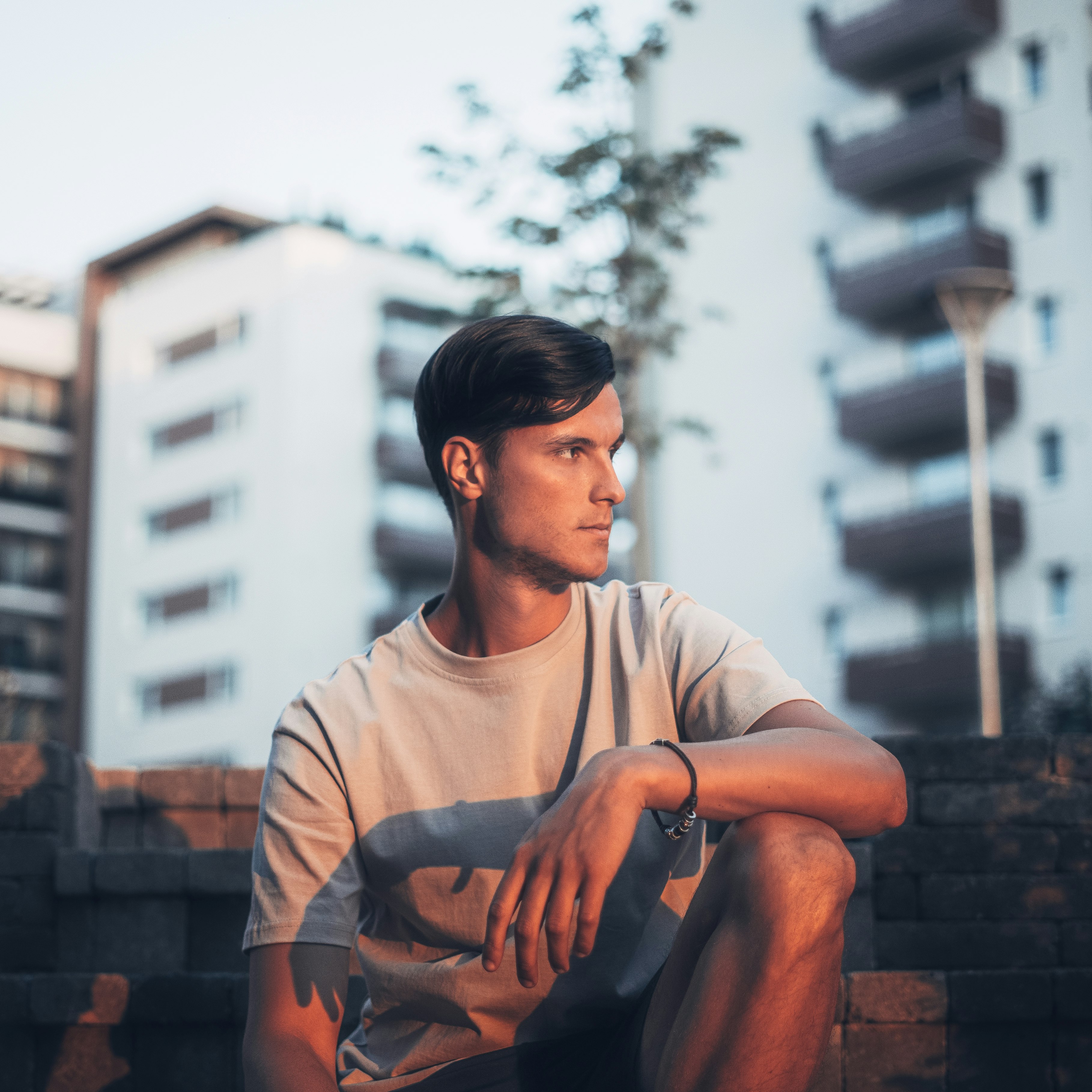 man in gray crew neck t-shirt and black pants sitting on brown concrete brick during